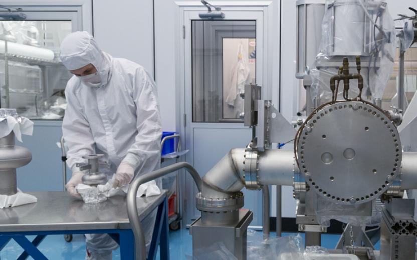 A scientist in a clean room works on a superconducting radio frequency (SRF) cavity.