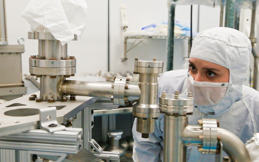 an image of a woman in a clean suit looking at beam components